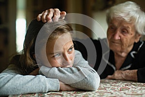 A little girl cries and her grandmother soothes stroking his hand on the head