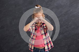 Little girl crying and covering eyes with hands