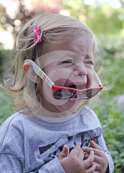 Little girl crying in the garden on spring background. Sad and angry concept