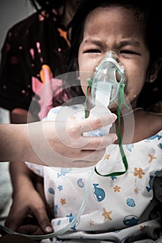 Little girl crying while getting in inhaler mask in hospital