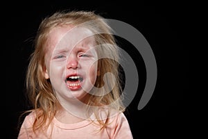 The Little Girl Is Crying Loudly, She Is Very Upset, She Is Hysterical. She Can't Calm Down. Photo In The Studio On A Dark