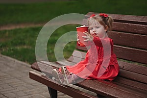 Little girl with cup of popcorn in park