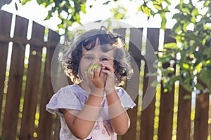 Little Girl with curly hair eating from an apple