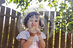 Little Girl with curly hair holding an apple