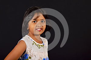 Little girl with a cute smile looking at camera against a black backdrop, Pune