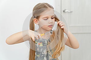 Little girl cutting hair to herself with scissors