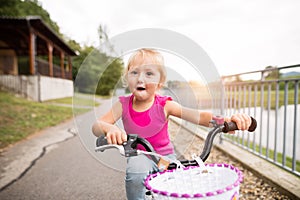 Little girl is cycling in the nature by the lake.