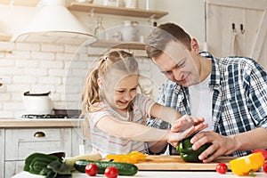 Little girl and dad having fun while cooking in kitchen