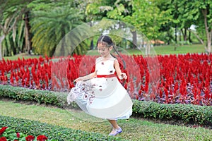 Little girl dance in flower garden. Asian little child having fun and play in park outdoor