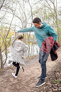 Little girl dances, holding dad`s hand on a walk in the woods