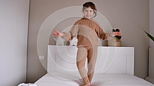 little girl dancing and having fun in the room on the bed