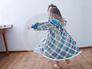 Little girl dancing at home. domestic child in green dress whirl