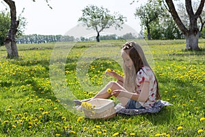 Little girl on dandelion lawn pick up dandelions in a basket