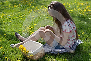 Little girl on dandelion lawn pick up dandelions in a basket