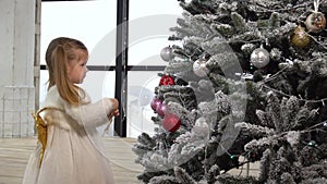 Little girl decorate Christmas tree with toys at home