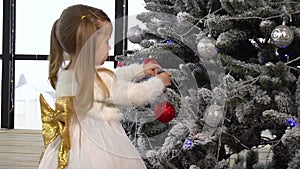 Little girl decorate Christmas tree using toys