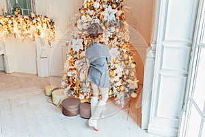 Little girl decorating Christmas tree on Christmas eve at home. Young kid in light bedroom with winter decoration. Happy family at