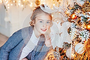 Little girl decorating Christmas tree on Christmas eve at home. Young kid in light bedroom with winter decoration. Happy family at