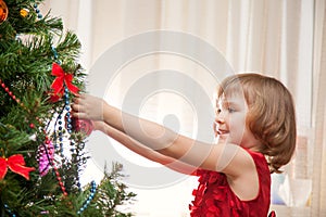 Little girl decorating christmas tree with toys