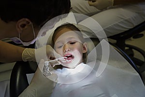 Little girl at dentist office, dentist applying antiseptic for dental treatment