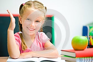 Little girl at the desk raised her hand