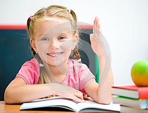 Little girl at the desk raised her hand