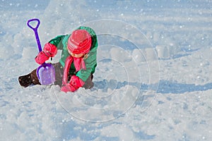 Little girl dig and play in winter snow