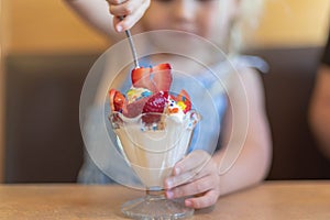 Little girl digging into an ice cream sundae