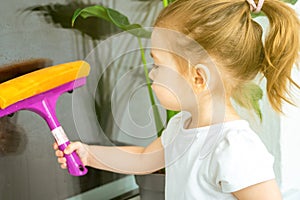 A little girl diligently washing a window