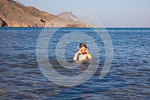 Little girl with diving glasses in the water of a beach in Andalusia