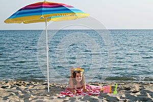 Little girl with diving mask under sunshade on beach