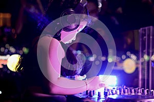 Little girl DJ playing live set and mixing music on controller turntable console mixing desk at stage in the night club, music