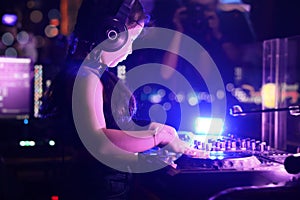 Little girl DJ playing live set and mixing music on controller turntable console mixing desk at stage in the night club, music