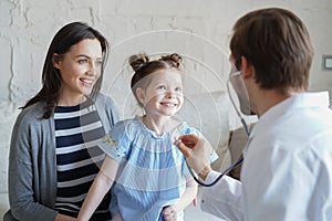 Little girl at the doctor for a checkup. Doctor auscultate the heartbeat of the child. photo