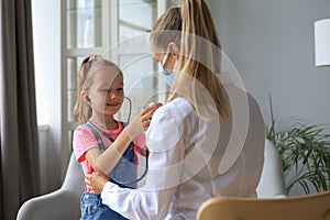 Little girl at the doctor for a checkup. Child auscultate the heartbeat of the doctor. photo