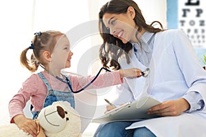 Little girl at the doctor for a checkup. Child auscultate the heartbeat of the doctor photo