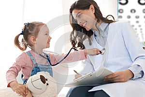 Little girl at the doctor for a checkup. Child auscultate the heartbeat of the doctor. photo