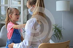 Little girl at the doctor for a checkup. Child auscultate the heartbeat of the doctor. photo