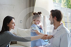 Little girl at the doctor for a checkup. The child auscultate the heartbeat of doctor for fun. photo