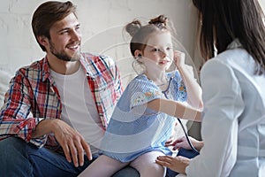 Little girl at the doctor for a checkup. The child auscultate the heartbeat of doctor woman for fun. photo