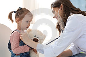 Little girl at the doctor for a checkup. Doctor woman auscultate the heartbeat of the child