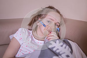 The little girl does inhalation at home. The girl is sick, is treated with inhalation