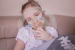 The little girl does inhalation at home. The girl is sick, is treated with inhalation