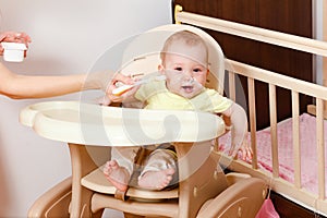 The little girl doesn`t want to eat. Baby sits in a feeding chair