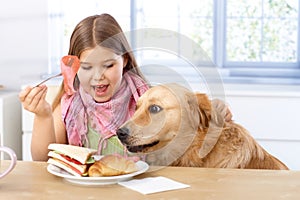 Little girl and dog having breakfast together