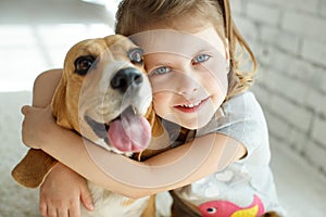 Little girl with a dog at home.