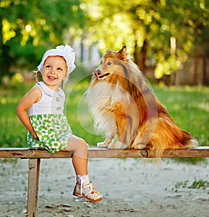 Little girl and dog sitting on a bench.