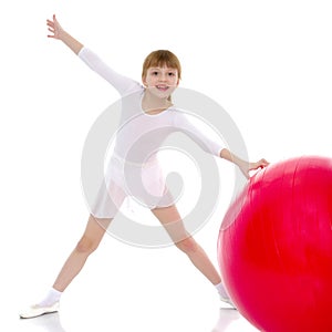Little girl doing exercises on a big ball for fitness.