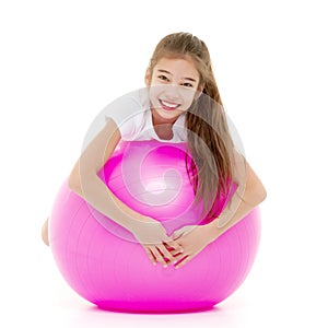 Little girl doing exercises on a big ball for fitness.