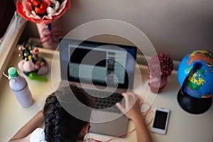 Little girl doing her homework on the laptop